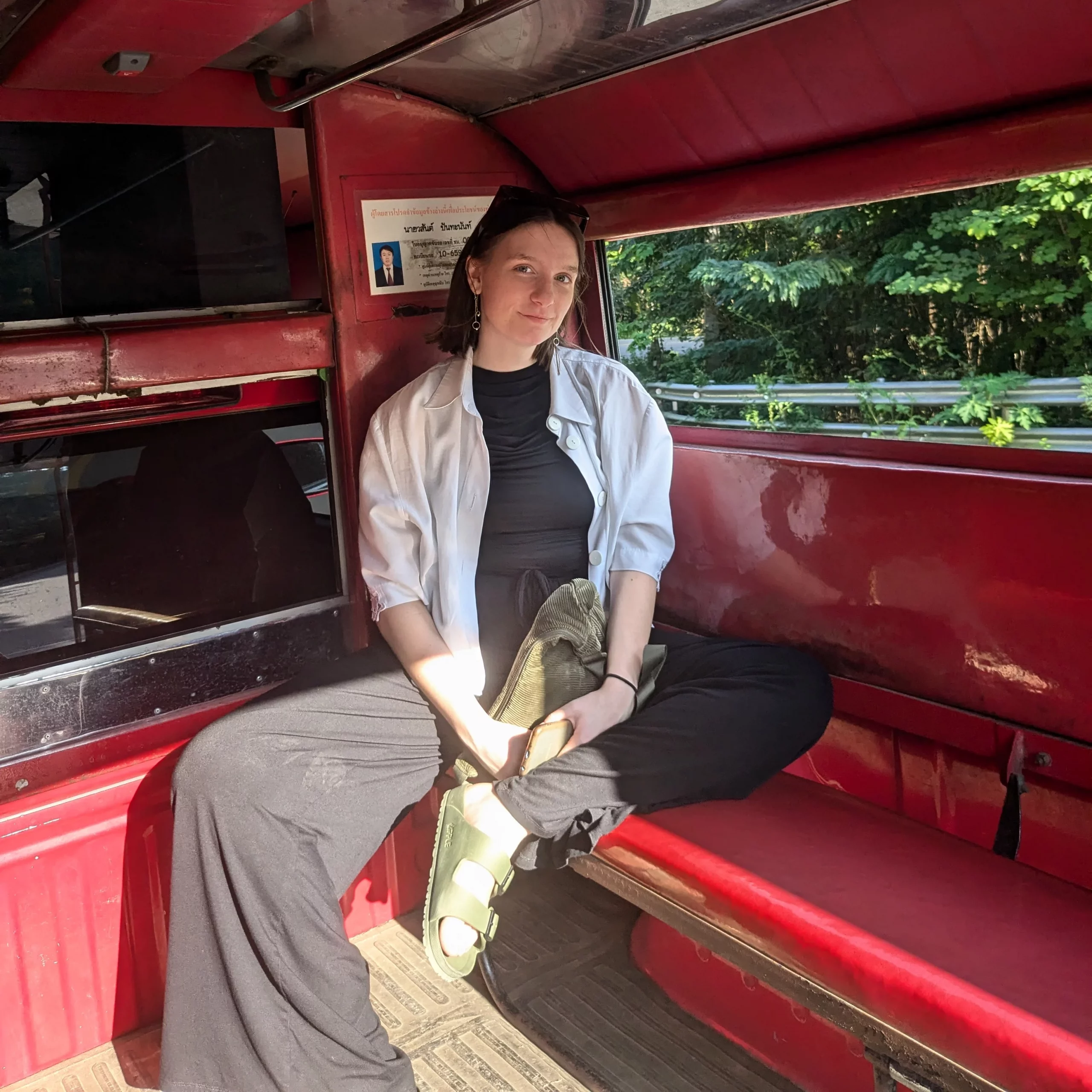 The photo shows Emily sitting in a red Songthaew