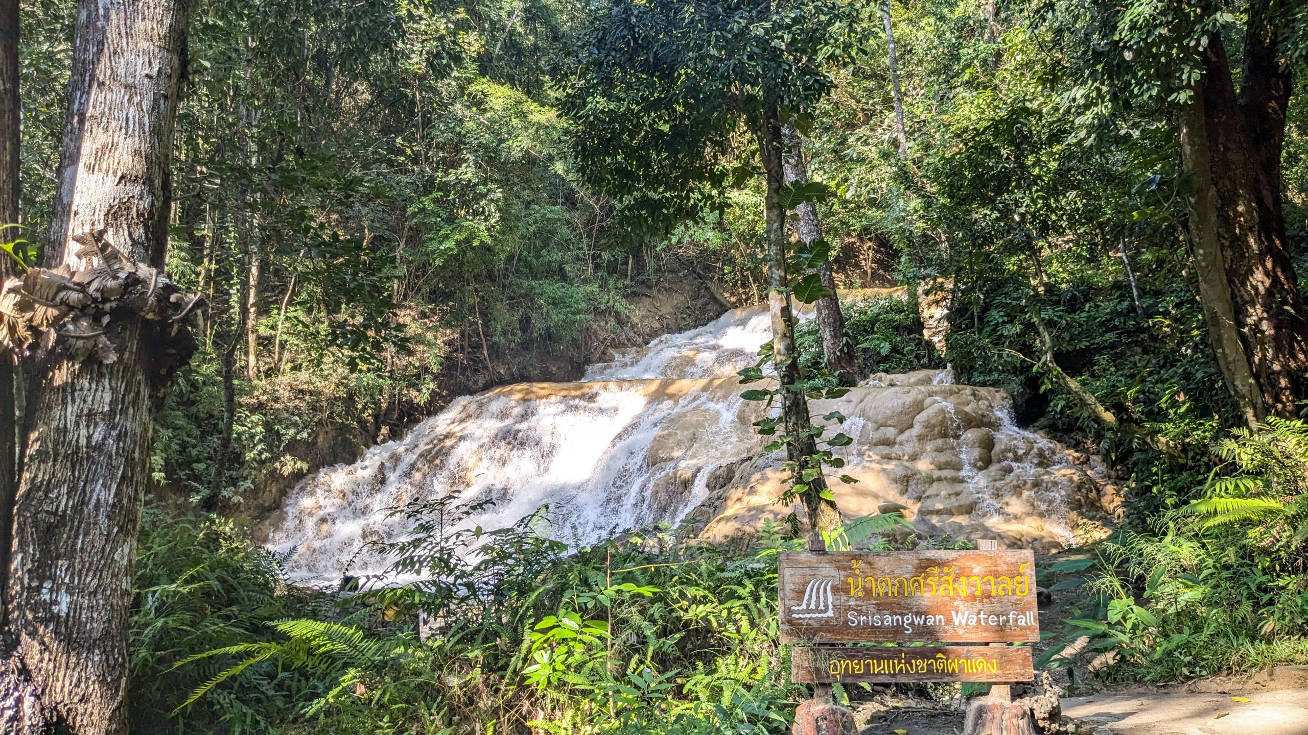 The image shows Srisangwan Waterfall surrounded by lush green jungle