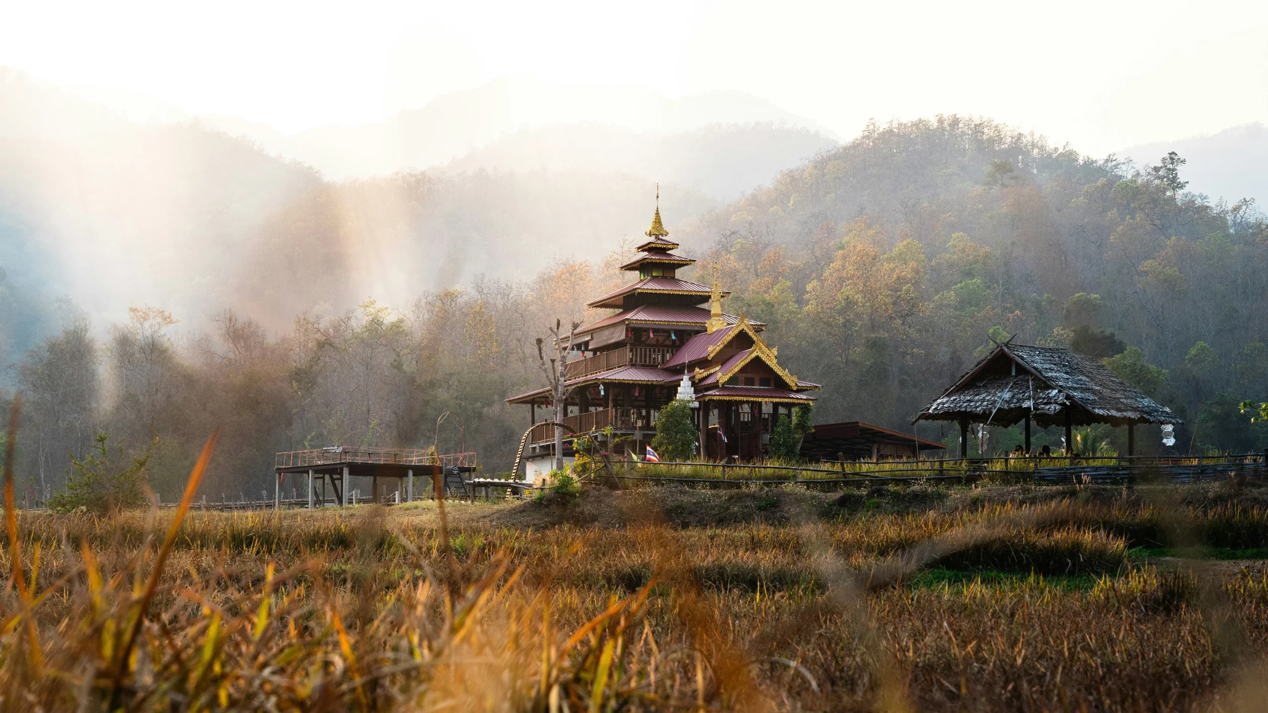 The main building along Kho Ku So Bamboo Bridge with mountains in the background