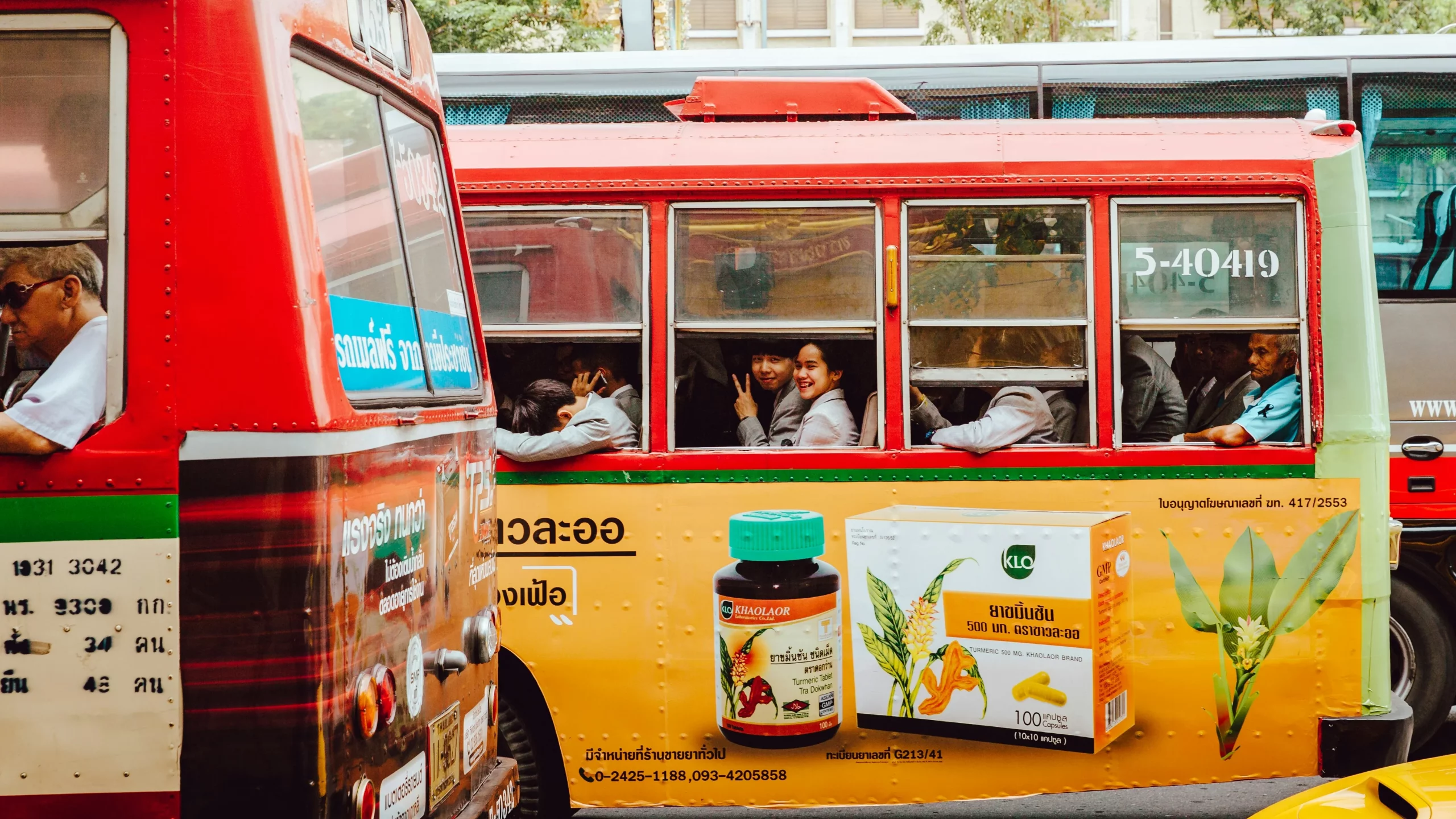 Two girls are smiling looking out of a bus going through Bangkok, Thailand