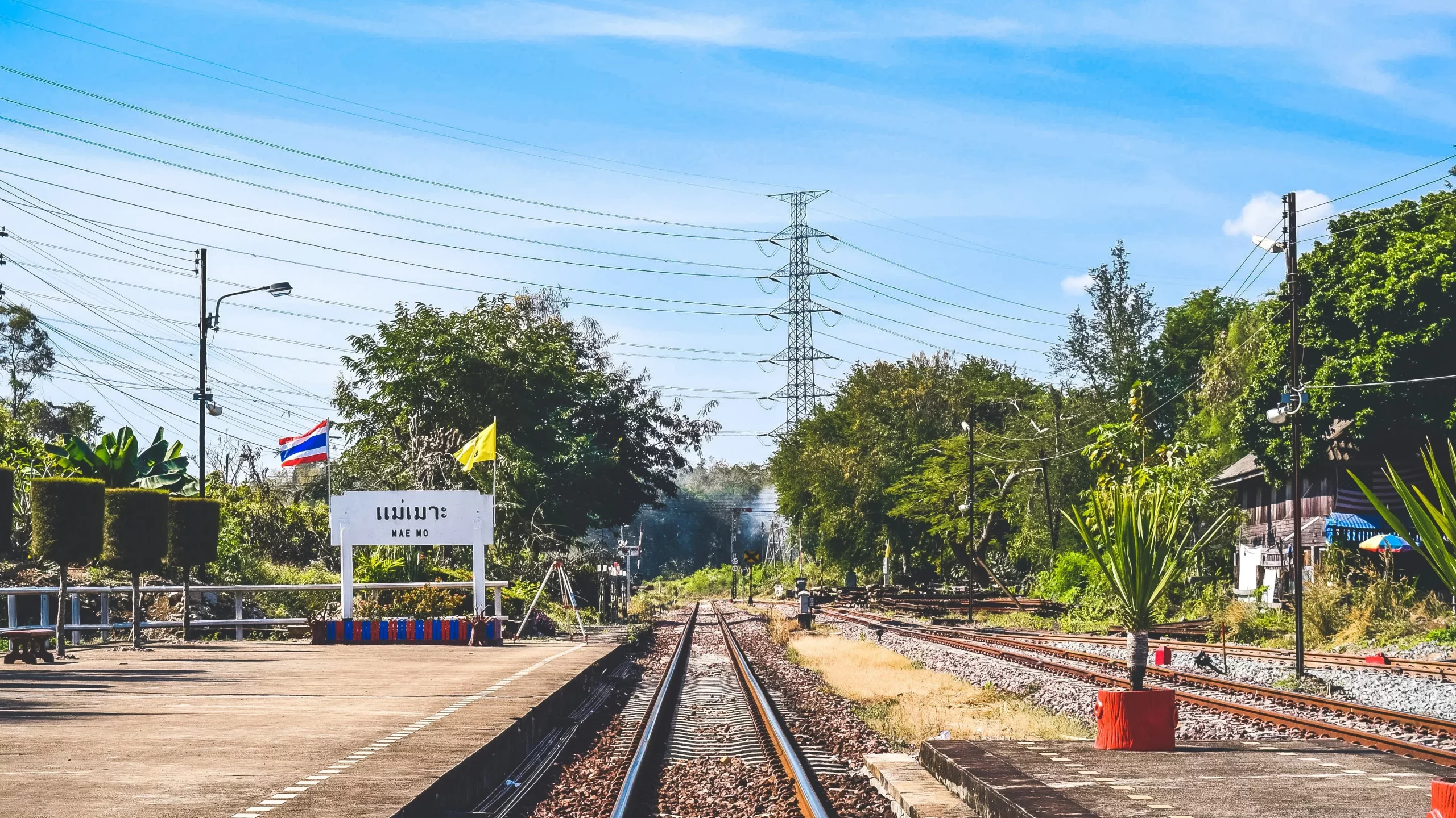 The image shows train tracks on a sunny day at the station Mae Mo, Lampang. 