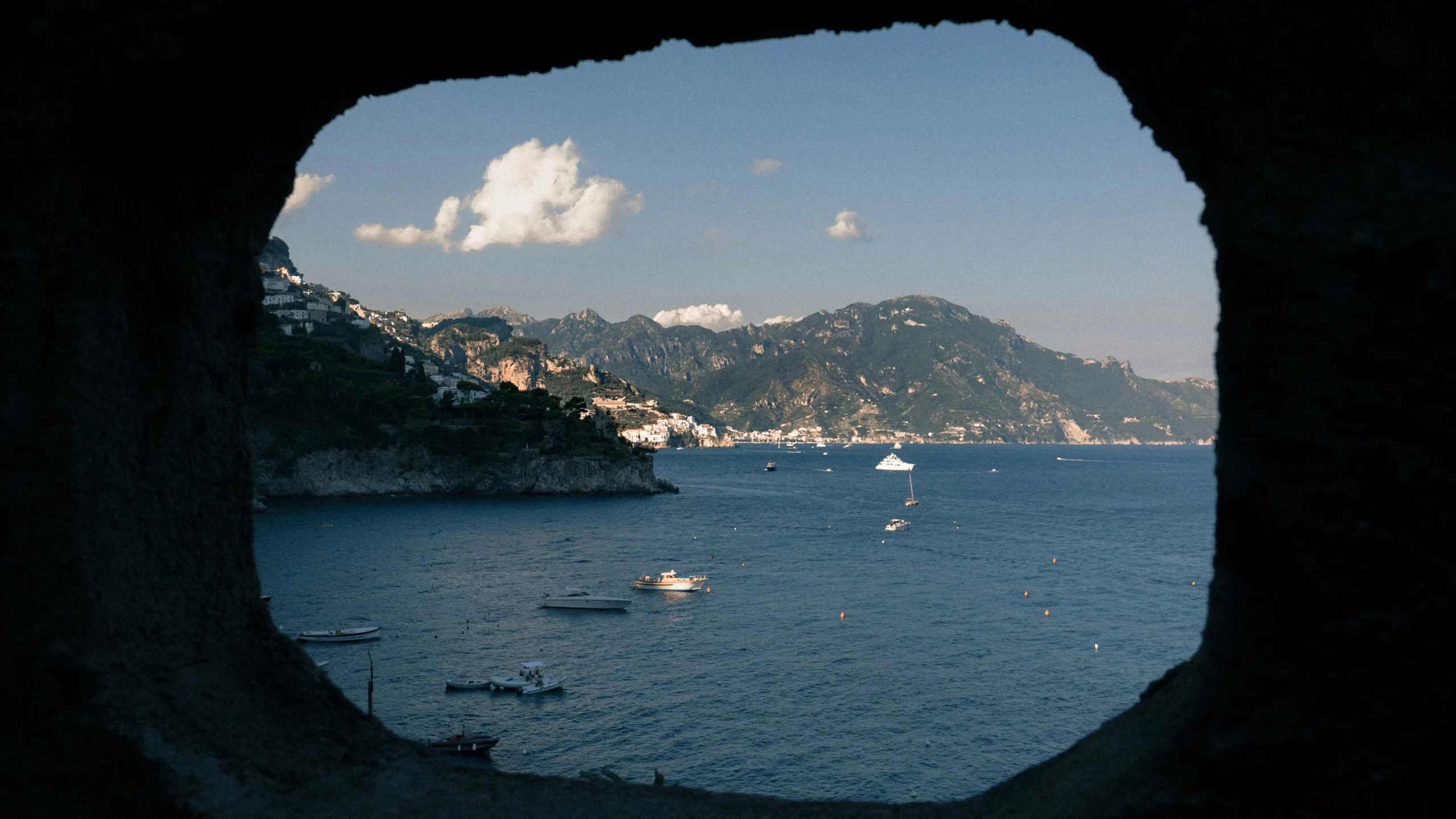 boats and ferrys in the ocean with mountains in the background